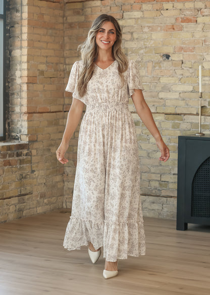 Floral maxi dress skirt in motion, showing the ruffled hem and flowing silhouette by a sunlit window.