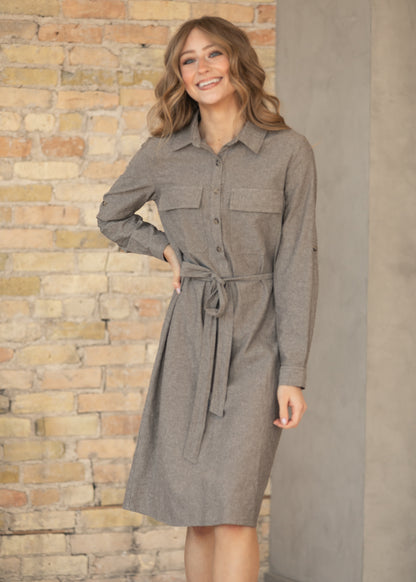 Woman wearing a brown dress with a stone wall background