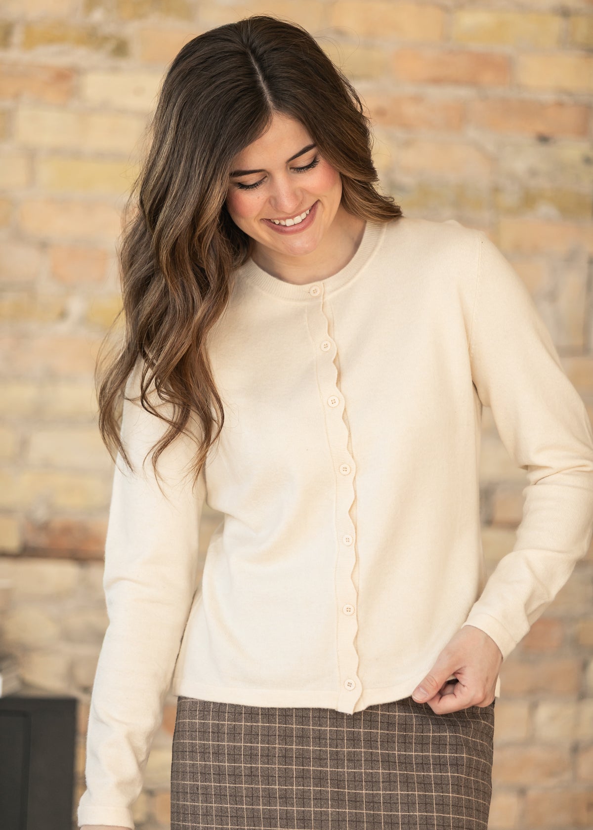 Ivory cardigan with scalloped button placket and soft fine knit fabric.