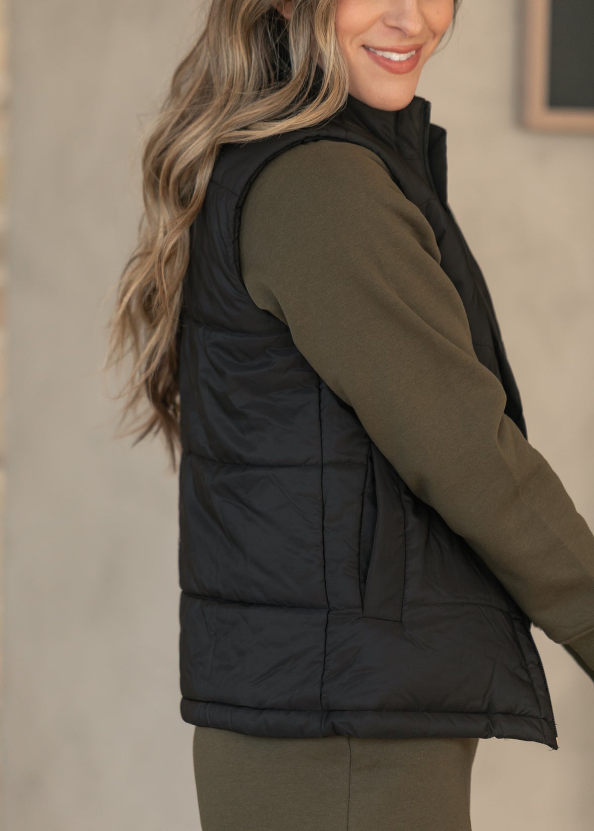 Black short puffer vest with side pockets and lightweight quilted design.