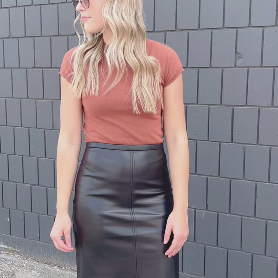 A black midi length faux leather skirt, with small back slit.