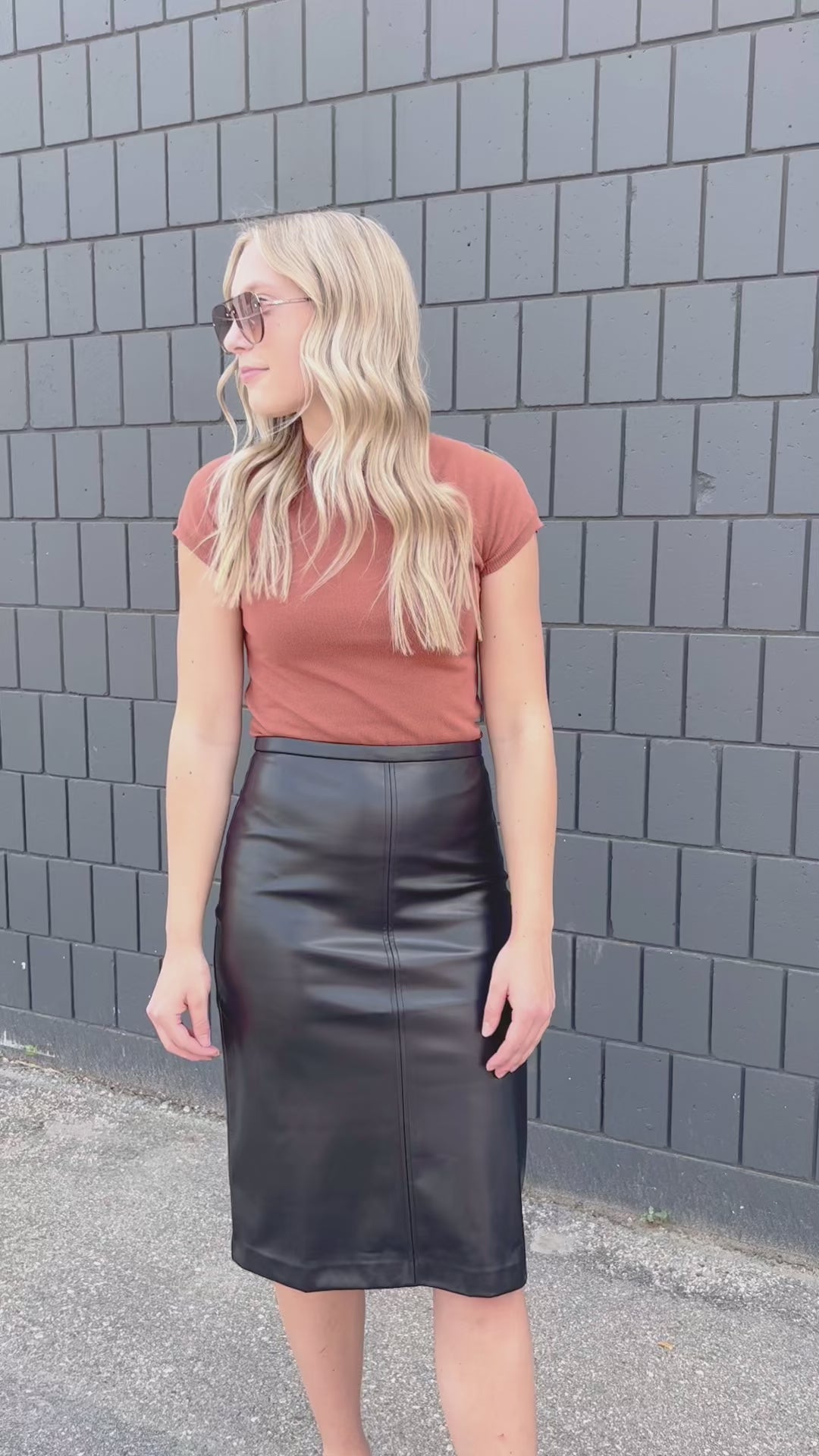 A black midi length faux leather skirt, with small back slit.