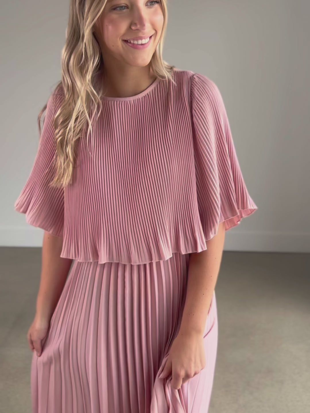 A pleated blush maxi dress with a blouson top and a-line skirt.