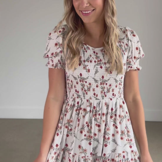 A smocked floral short sleeve midi dress with a round neckline, and tiered skirt.
