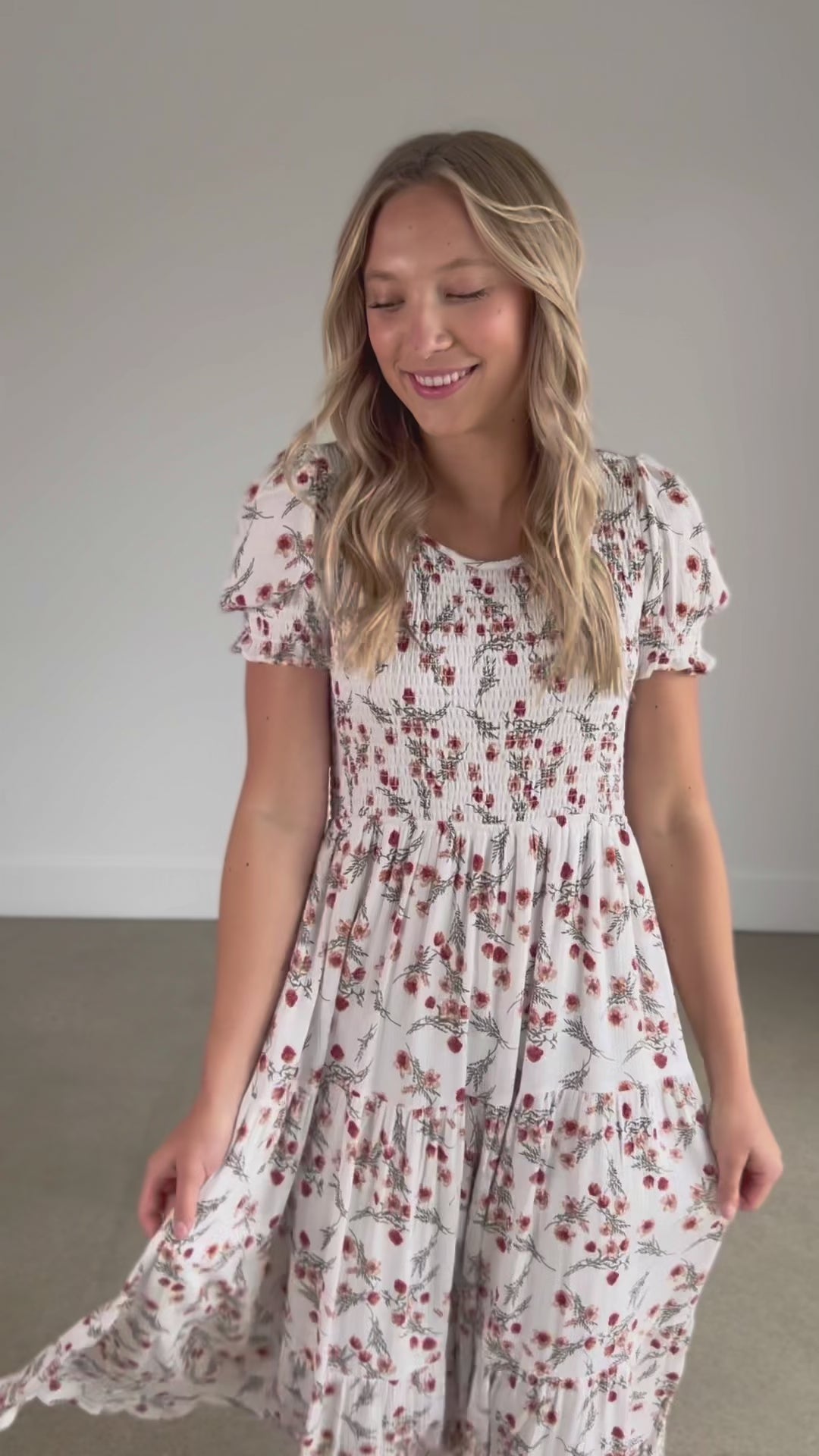 A smocked floral short sleeve midi dress with a round neckline, and tiered skirt.