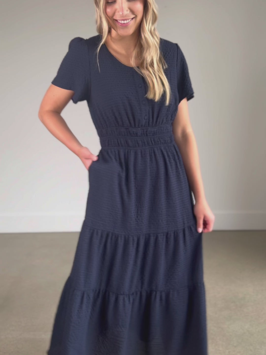 A textured navy short sleeve maxi dress with a nursing friendly bodice, smocked waist, and tiered skirt.