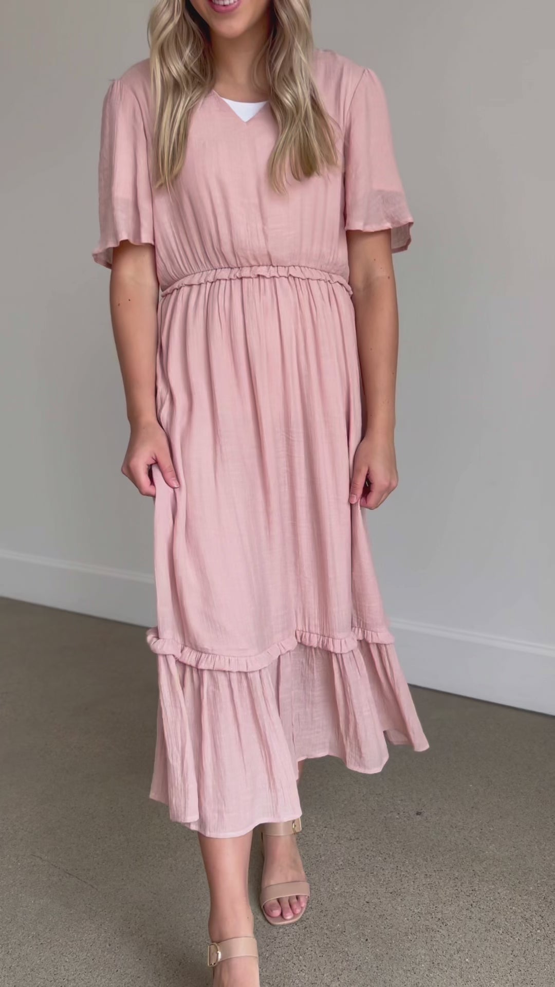 A pink v-neck ruffle maxi dress with flutter sleeves, and ruffles at the waist and hem.