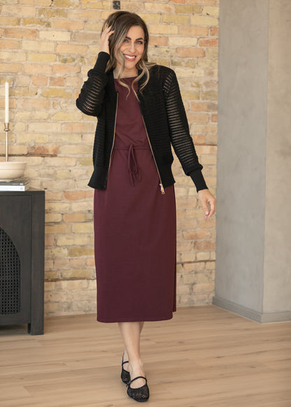Back of mulberry midi dress showing a short side slit, styled with a cropped denim jacket and black flats.