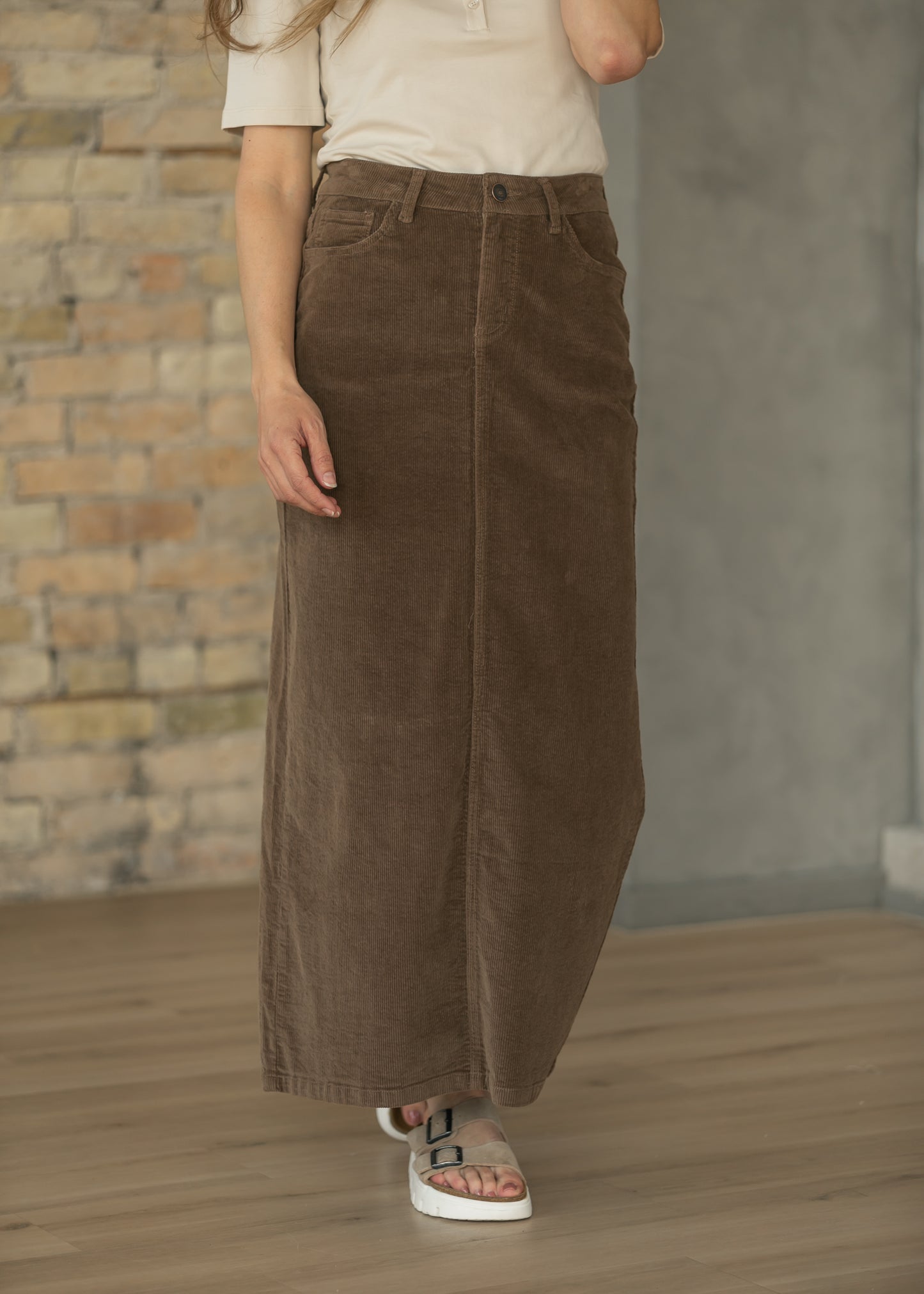 Brown corduroy maxi skirt styled with a cream short sleeve top and casual sneakers.