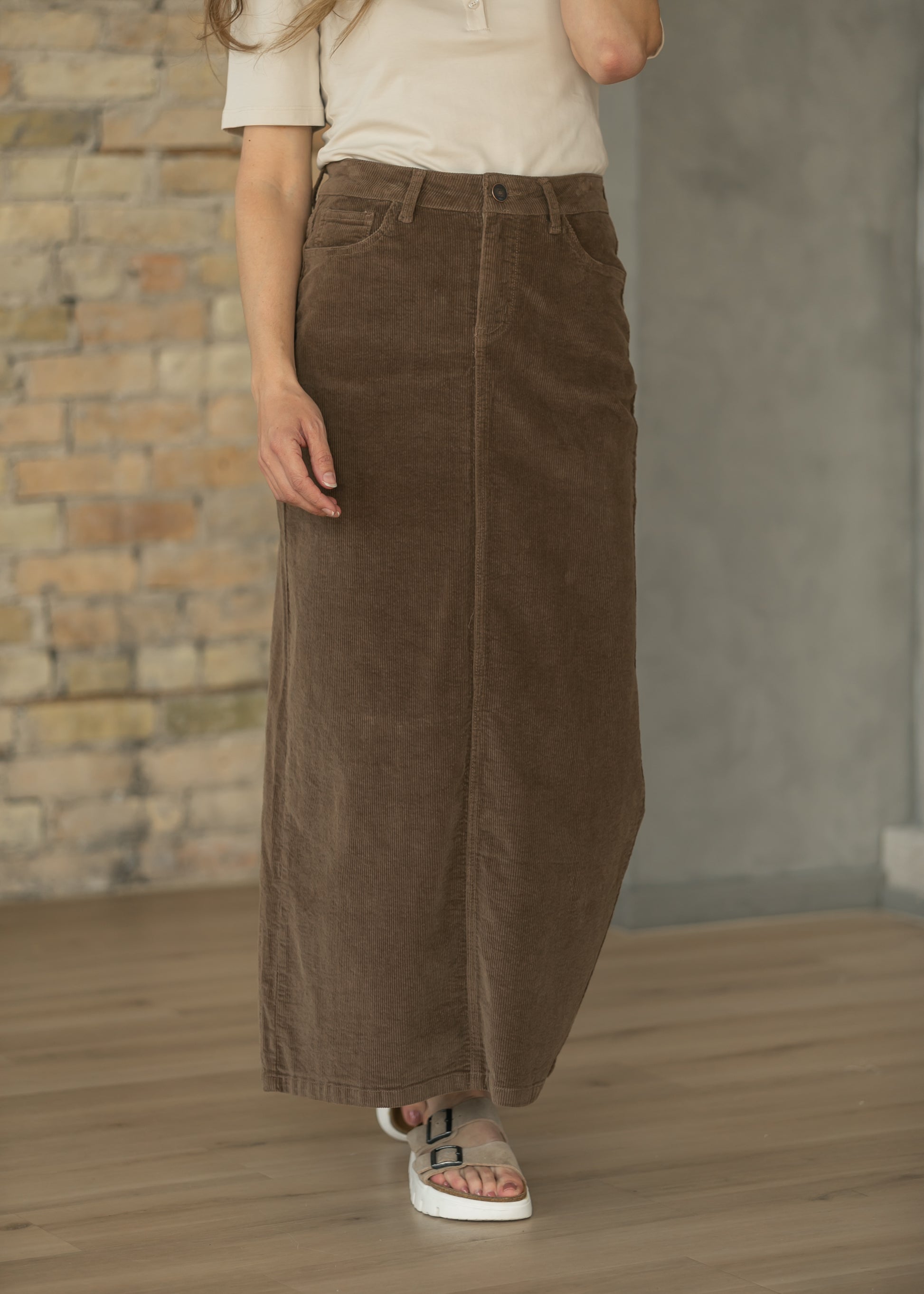 Brown corduroy maxi skirt styled with a cream short sleeve top and casual sneakers.