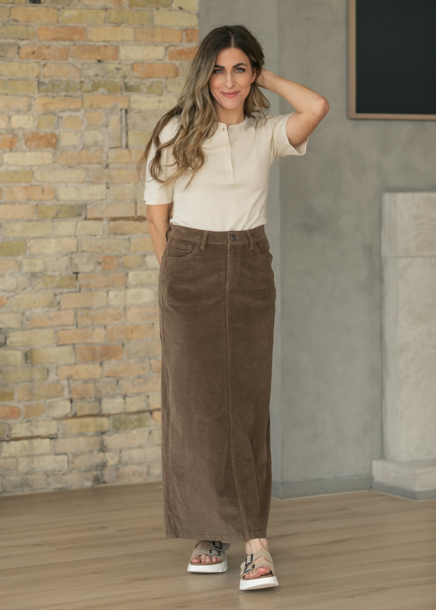 Brown corduroy maxi skirt styled with a cream short sleeve top and sneakers for everyday wear.