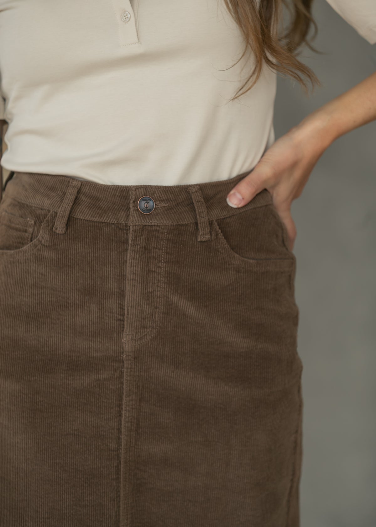 Close-up of brown corduroy maxi skirt showing front pocket, waistband, belt loops, and corduroy texture.