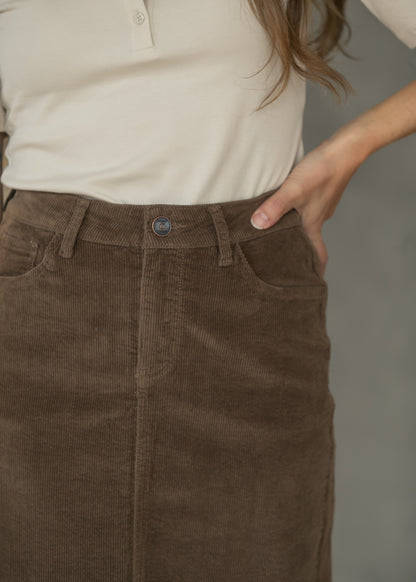 Close-up of brown corduroy maxi skirt showing front pocket, waistband, belt loops, and corduroy texture.