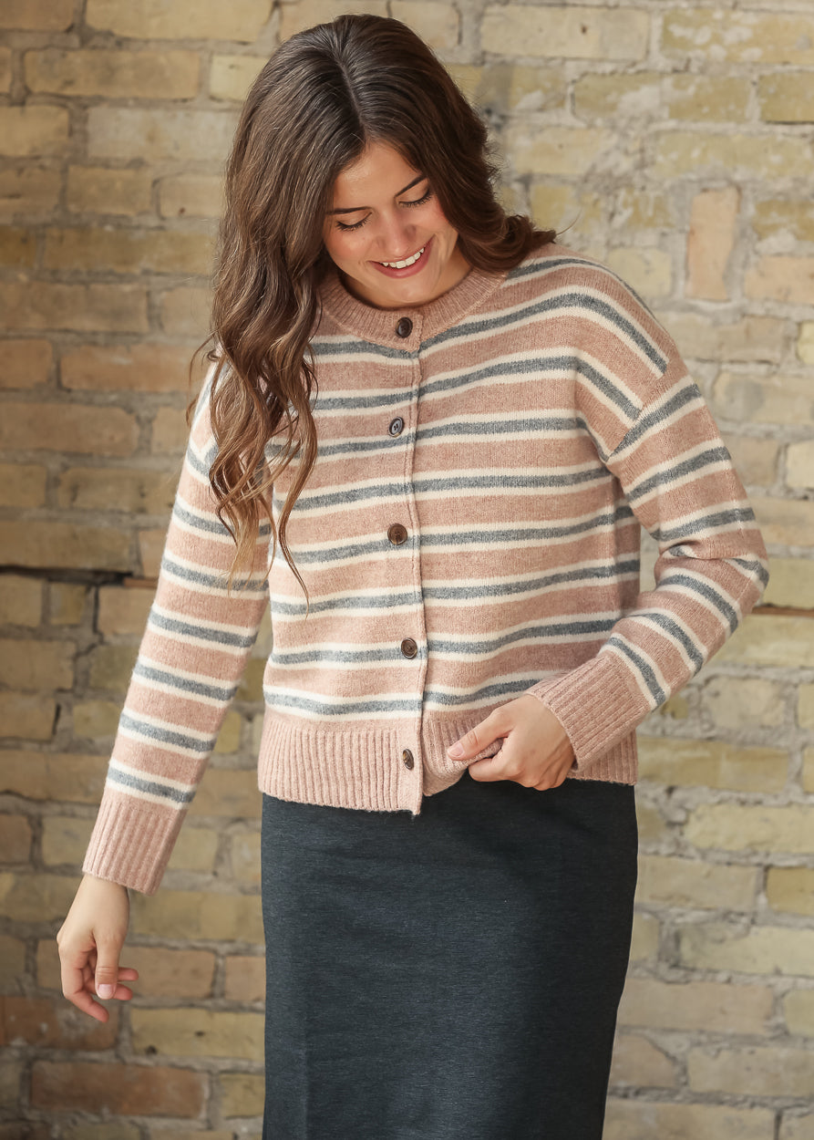 Model wearing a pink, cream, and gray striped button-front cardigan with a black maxi skirt, front view