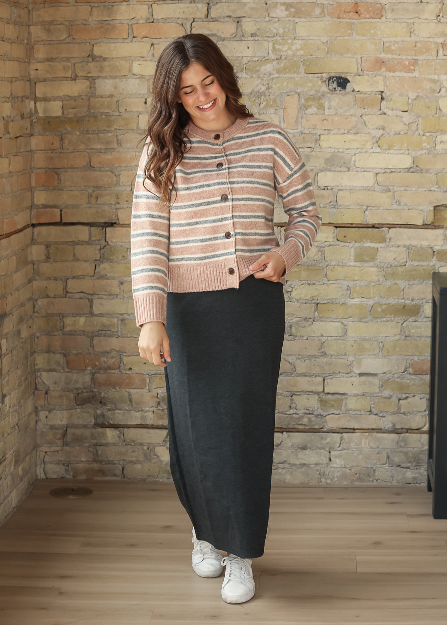 Full-length view of striped cardigan styled with a black maxi skirt and white sneakers