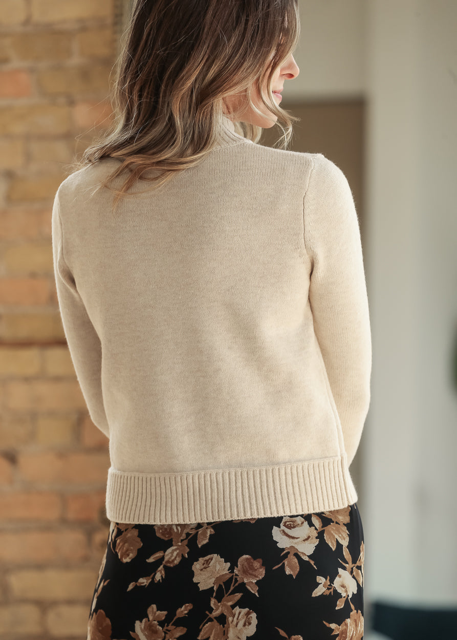 Back view of cream mock neck sweater styled with a black floral skirt