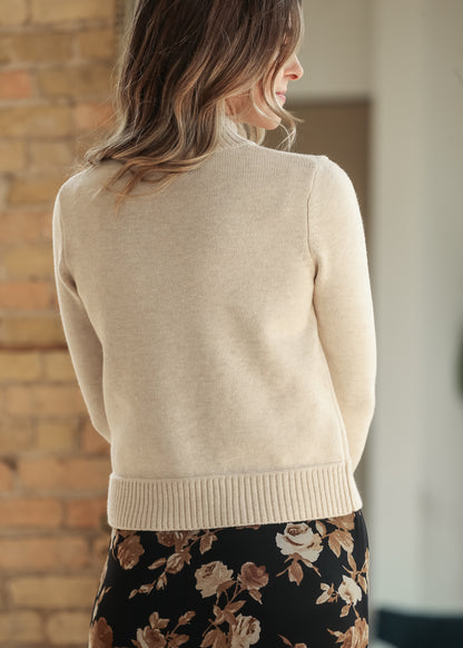 Back view of cream mock neck sweater styled with a black floral skirt