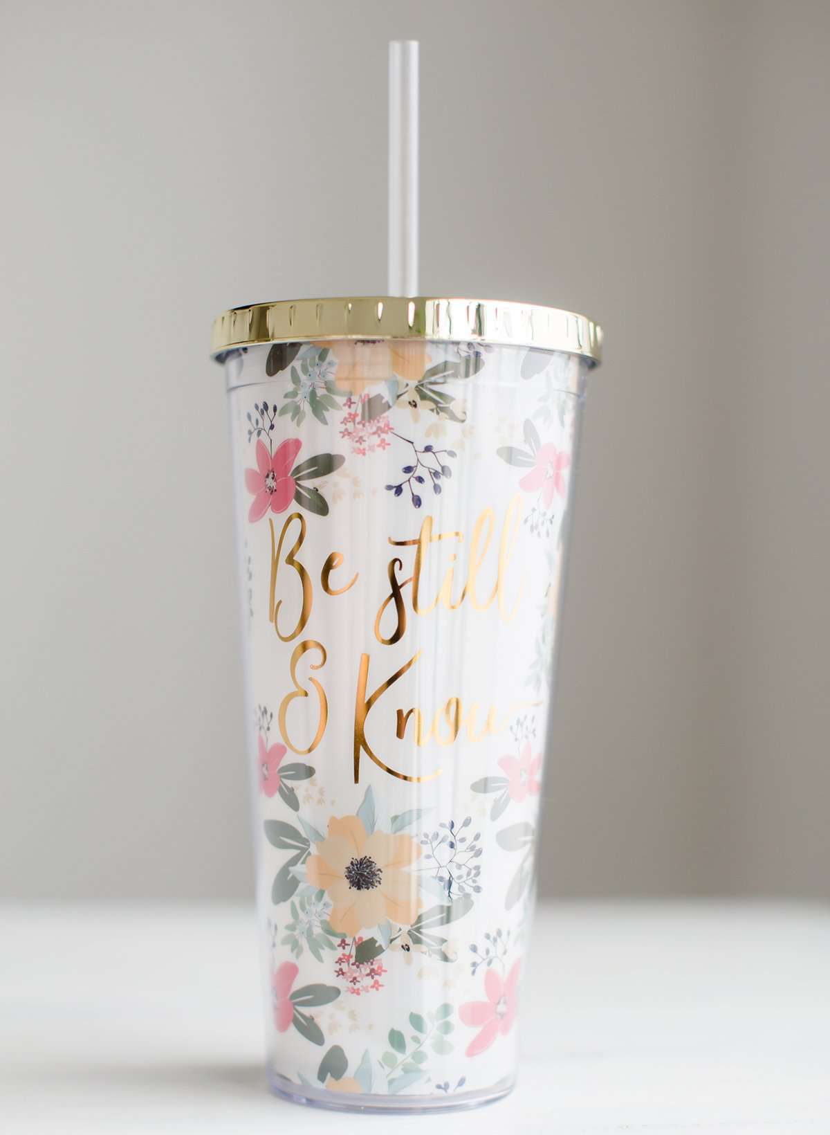 Be still and know double wall tumbler. This tumbler has flowers adorning it and accented with a gold cap and gold writing.