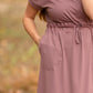 This is a Cinch Waist Athletic midi dress in a purpley taupe color that has a mesh detail and large side pockets. 