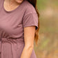 This is a Cinch Waist Athletic midi dress in a purpley taupe color that has a mesh detail and large side pockets. 