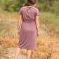 This is a Cinch Waist Athletic midi dress in a purpley taupe color that has a mesh detail and large side pockets. 