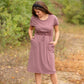 This is a Cinch Waist Athletic midi dress in a purpley taupe color that has a mesh detail and large side pockets. 
