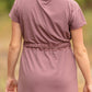 This is a Cinch Waist Athletic midi dress in a purpley taupe color that has a mesh detail and large side pockets. 