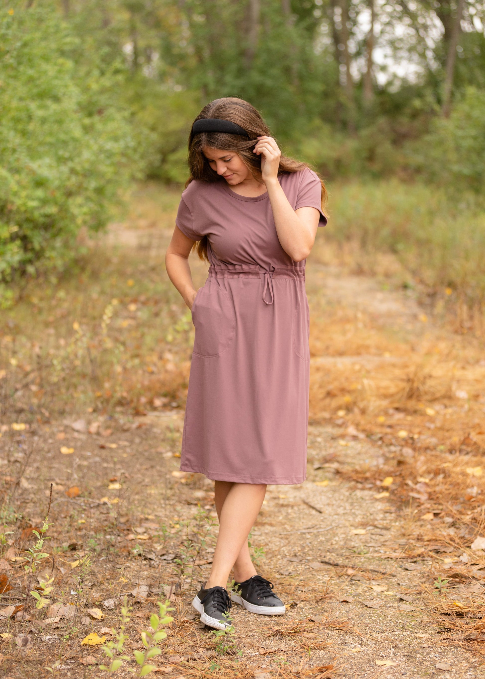 This is a Cinch Waist Athletic midi dress in a purpley taupe color that has a mesh detail and large side pockets. 