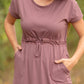This is a Cinch Waist Athletic midi dress in a purpley taupe color that has a mesh detail and large side pockets. 