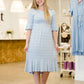 Woman wearing a modest baby blue and white striped midi dress with ruffles on the hem and sleeves