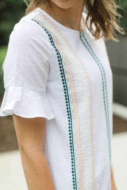 Modest white belle-sleeve top with Earthy colored embroidery down the front.