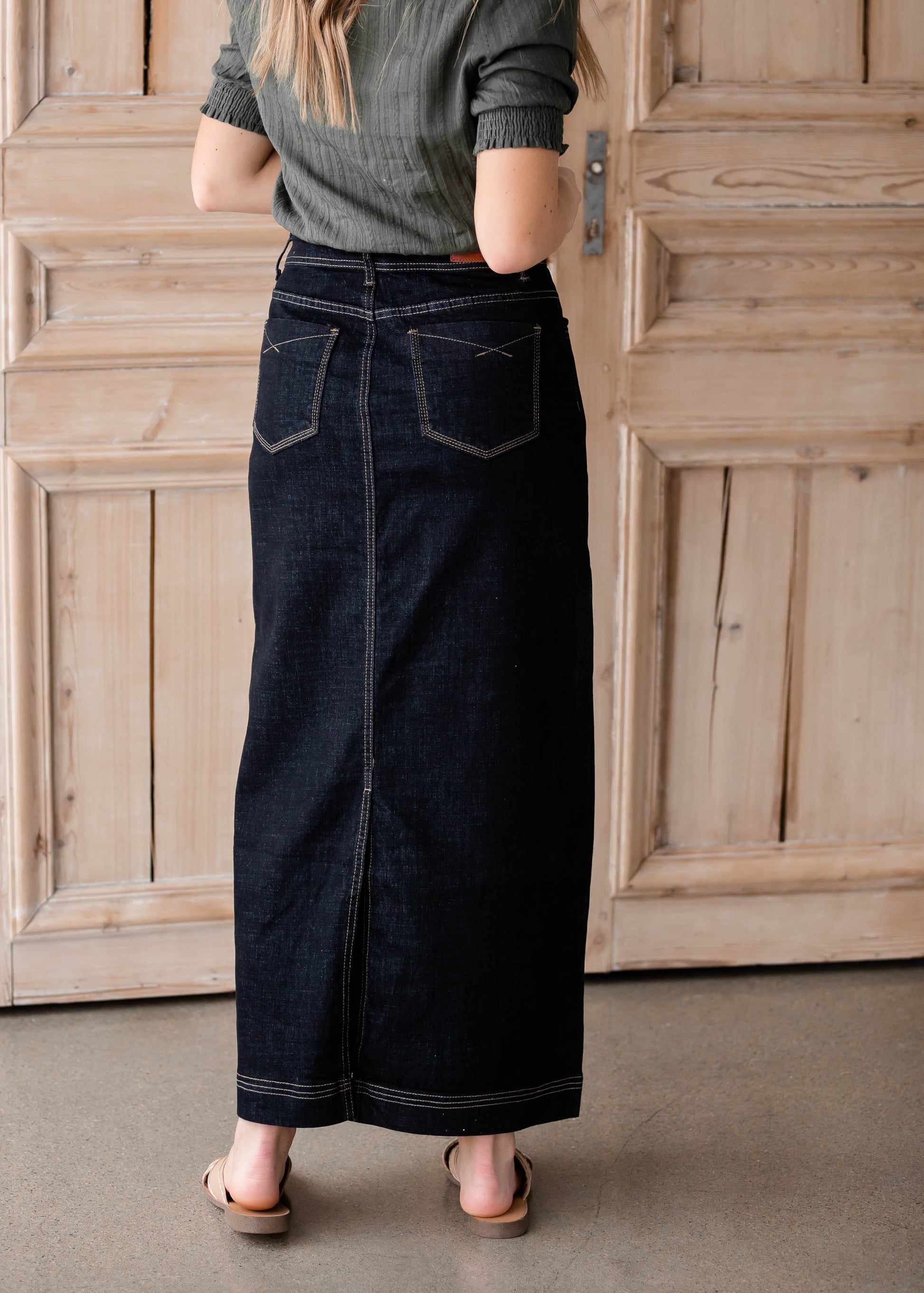 The Beth Dark Wash Long Denim Skirt is an Inherit Design made with you in mind! The dark wash is easy to dress up and details make this a stand out skirt! There is a triple stitch detail on the bottom hem and an Inherit logo patch on the back waistband! A straight fit with a slit in the back makes this long denim skirt super easy to move in and to pair with any tops!