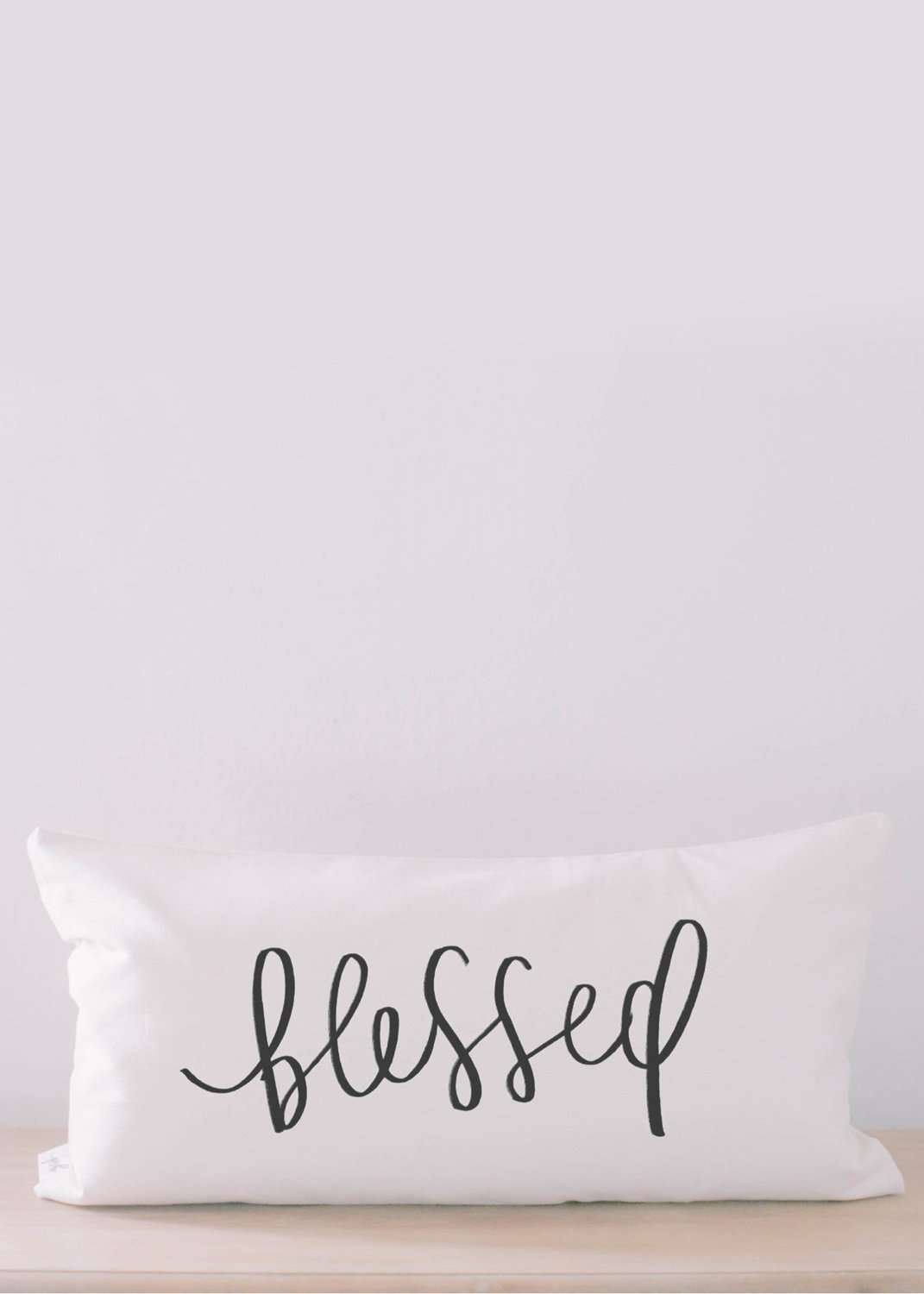 White lumbar pillow with the words blessed on it