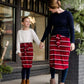 Woman wearing a modest mustard and burgandy striped midi skirt. This skirt has a fabric belt that is removable and is also mommy and me styled. This skirt is paired with tights and boots.