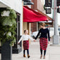 Woman wearing a modest mustard and burgandy striped midi skirt. This skirt has a fabric belt that is removable and is also mommy and me styled. This skirt is paired with tights and boots.