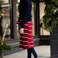 Woman wearing a modest mustard and burgandy striped midi skirt. This skirt has a fabric belt that is removable and is also mommy and me styled. This skirt is paired with tights and boots.