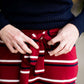 Woman wearing a modest mustard and burgandy striped midi skirt. This skirt has a fabric belt that is removable and is also mommy and me styled. This skirt is paired with tights and boots.