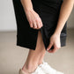 A black midi skirt with a drawstring waist, ribbed hem, pockets, and bottom side zipper.