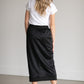A black midi skirt with a drawstring waist, ribbed hem, pockets, and bottom side zipper.