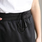 A black midi skirt with a drawstring waist, ribbed hem, pockets, and bottom side zipper.