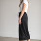 A black midi skirt with a drawstring waist, ribbed hem, pockets, and bottom side zipper.