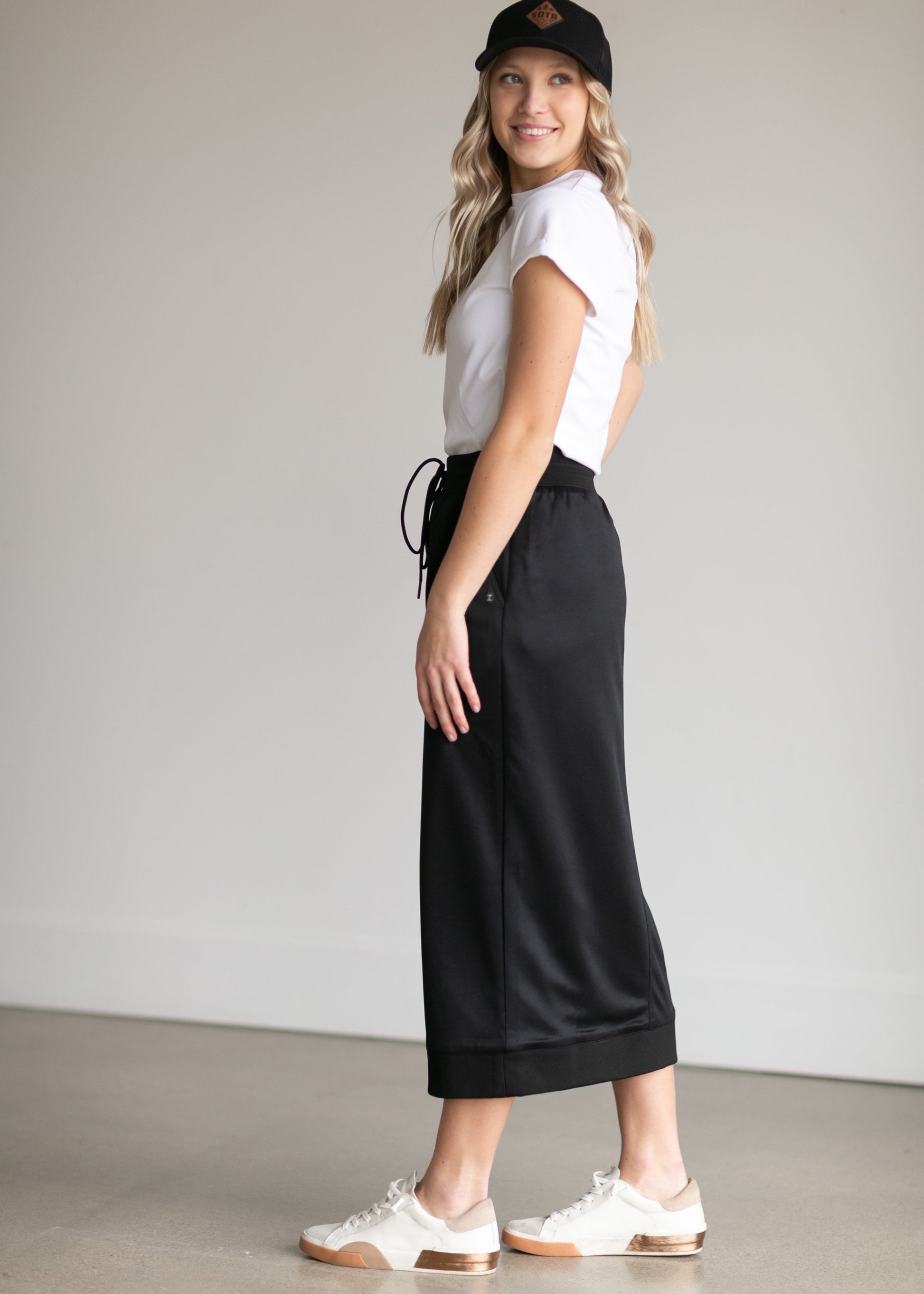 A black midi skirt with a drawstring waist, ribbed hem, pockets, and bottom side zipper.