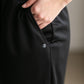 A black midi skirt with a drawstring waist, ribbed hem, pockets, and bottom side zipper.