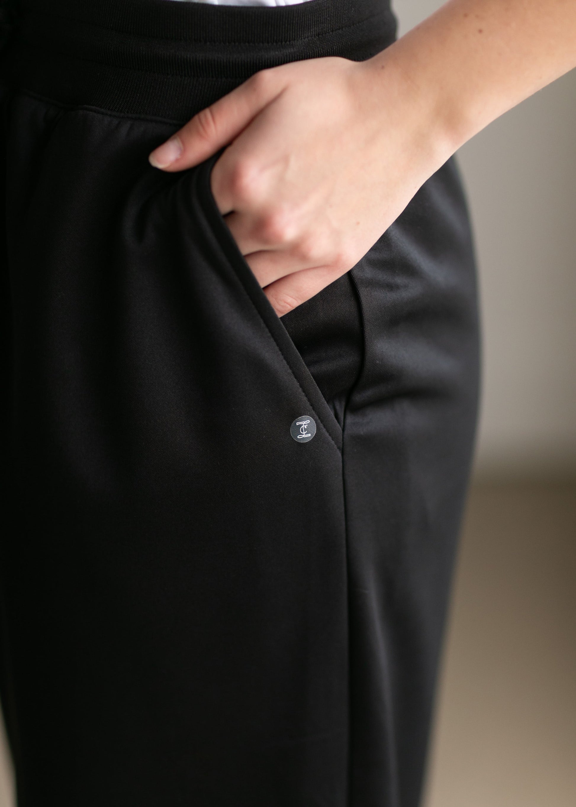 A black midi skirt with a drawstring waist, ribbed hem, pockets, and bottom side zipper.