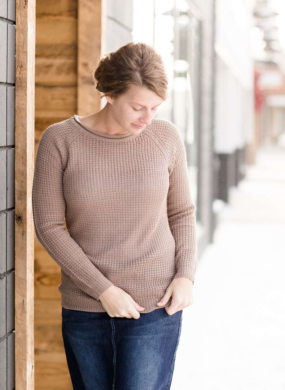Woman wearing a waffle knit sweater that has a rollover neck hem and raglan style long sleeves. It is 100% acrylic and comes in mauve, navy, Burgundy and khaki.