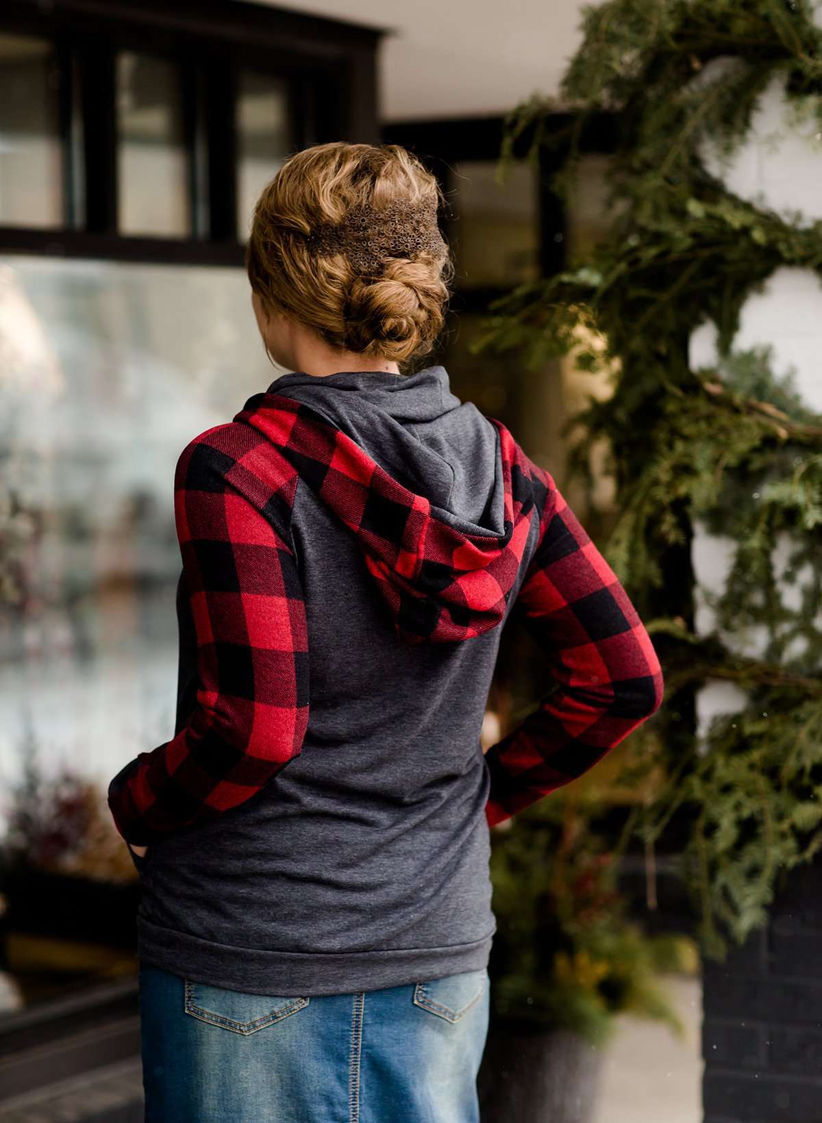 Woman at Inherit Clothingn Company wearing a charcoal and buffalo check hooded top with front kangaroo pocket.
