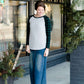 Woman wearing a black and green buffalo check sleeve raglan top paired with a long modest jean skirt standing outside of Inherit Clothing Company!