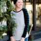 Woman wearing a black and green buffalo check sleeve raglan top paired with a long modest jean skirt standing outside of Inherit Clothing Company!