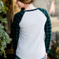 Woman wearing a black and green buffalo check sleeve raglan top paired with a long modest jean skirt standing outside of Inherit Clothing Company!