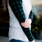 Woman wearing a black and green buffalo check sleeve raglan top paired with a long modest jean skirt standing outside of Inherit Clothing Company!